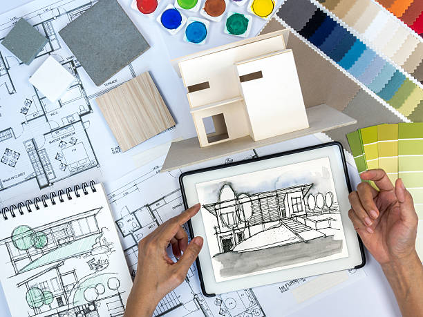 Architect, interior designer working at worktable with tablet, home model stock photo