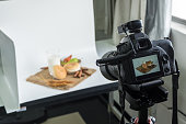 Camera shooting bread and glass of milk in indoor studio