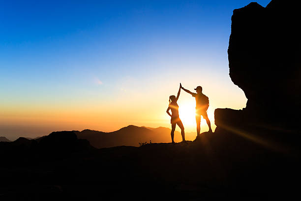 trabalho em equipe de escalada ajuda casal  - climbing clambering mountain silhouette - fotografias e filmes do acervo