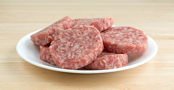 Sausage patties on a white plate atop a table