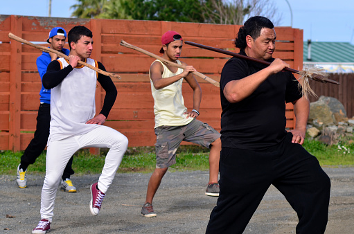Kaitaia, New Zealand - August 15, 2013: Maori chief teaches young men Mau Rakau martial art in the street on August 15, 2013. It's  ancient Maori martial art that teaches the use of the Taiaha and other Maori weapons in face to face combat.