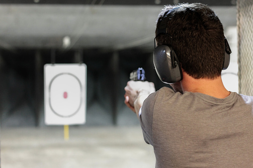 Hombre de disparo de pistola con el objetivo de la usp en el intervalo de tiro bajo techo photo