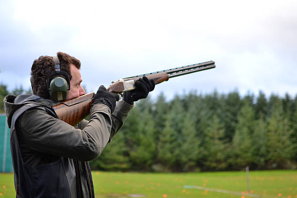 man shooting shotguns at clay pigeon outdoors Shot in the Isle Of Man target shooting photos stock pictures, royalty-free photos & images