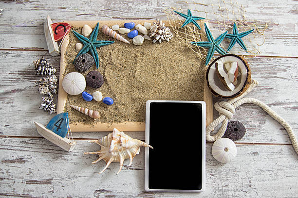 istock Smartphone on wood and sea sand with starfish and shells. 540375534