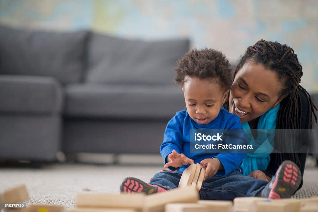 Playing with Wooden Blocks A mother is spending quality time with her toddler son on mother's day. They are laughing and playing together. Blue Stock Photo