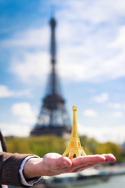 istock Eiffel Tower souvenir held out against the real Eiffel Tower 540380130