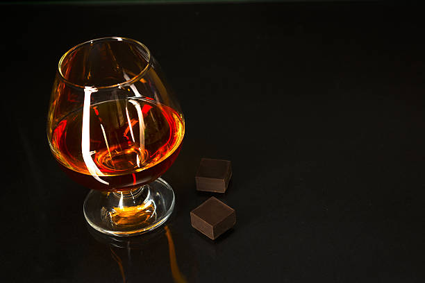 istock Brandy glass and chocolate on black background 540380692