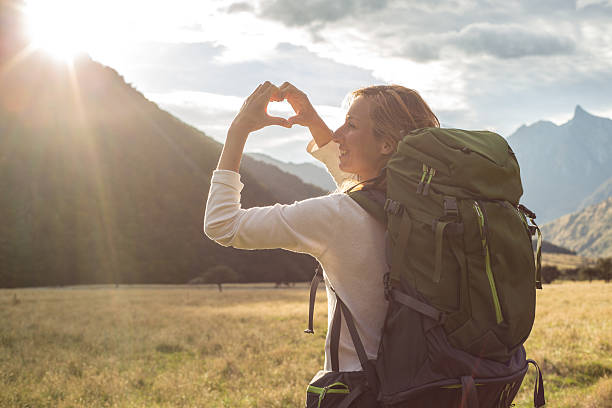 istock Female makes heart shape finger frame over mountain landscape 540383308