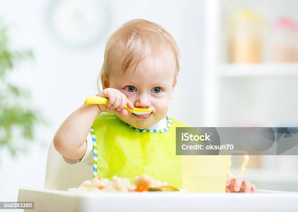 Baby Child Sitting In Chair With A Spoon Stock Photo - Download Image Now - Baby - Human Age, Eating, Baby Food