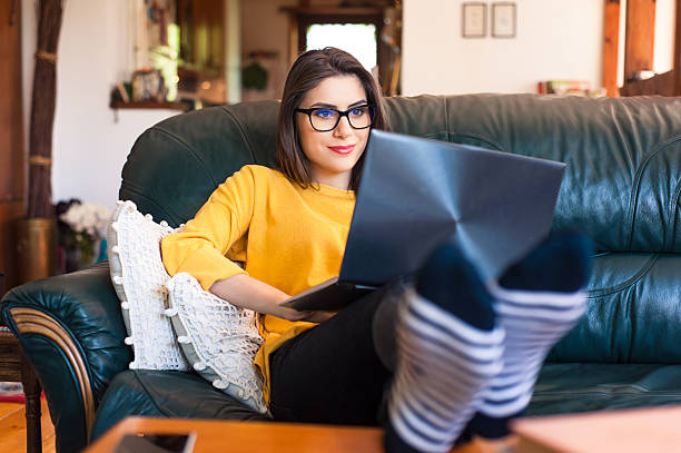 Woman sitting on the couch using a laptop.