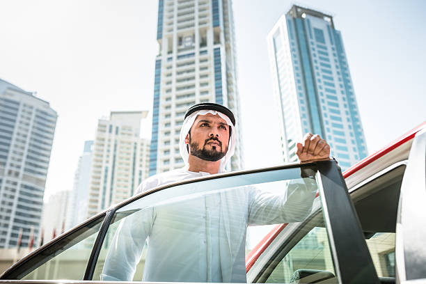 arabe cheik debout à l'extérieur de la station de taxi - middle eastern ethnicity sheik wealth men photos et images de collection