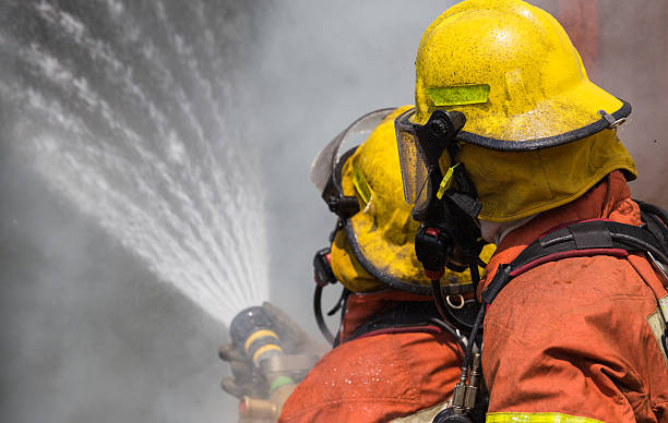 istock two firemen in helmet and oxygen mask spraying water 540391006