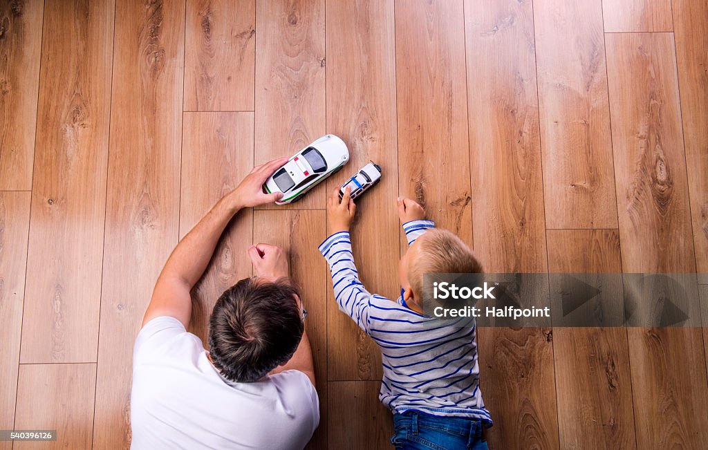 Unrecognizable father with his son playing with cars Unrecognizable father with his son playing with cars. Studio shot on wooden background. Car Stock Photo