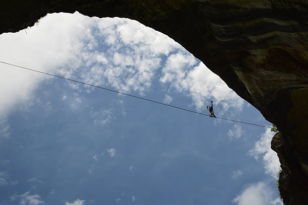 Young highline walker on tightrope high in the sky Karlukovo, Bulgaria – June 12, 2016: Young highliner walking on tightrope high on the rocks of Prohodna Cave highlining stock pictures, royalty-free photos & images