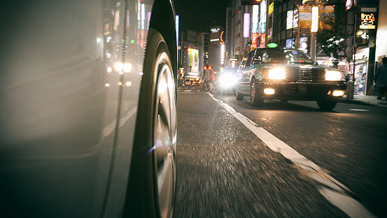 A low angle view from the tire of a car driving through the Shibuya area of Tokyo, Japan.