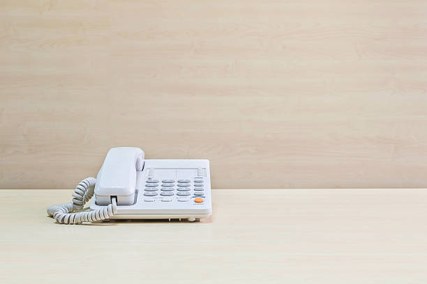 istock Closeup white office phone on blurred wooden desk and wall 540399254