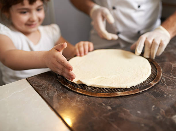 Girl corrects hand edge of  pancake pizza