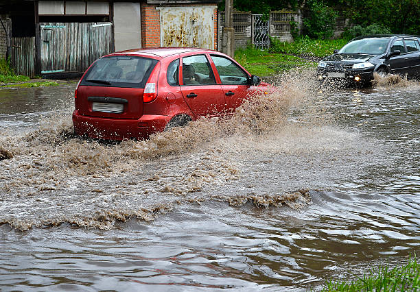 Car rides in heavy rain on a flooded road