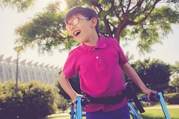 Disability child, walking sticks, cerebral palsy, smiling Nine year boy enjoying a walk in a sunny park using walking frame mobility walker stock pictures, royalty-free photos & images