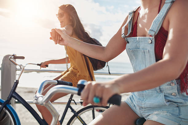 istock Two female friends holding hands and riding cycles 540487950