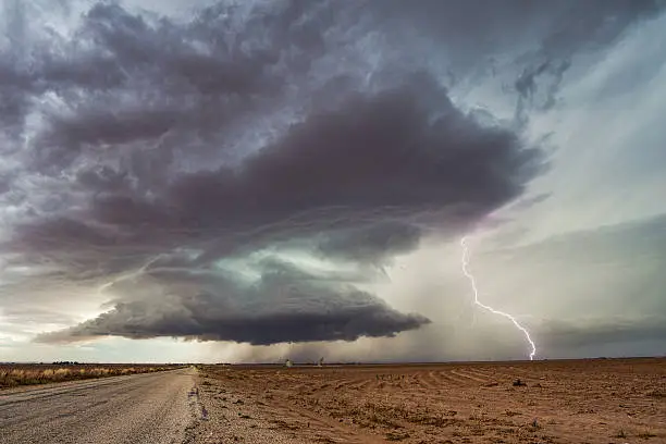Dramatic dark clouds spin beneath an approaching supercell thunderstorm with intense lightning near Ackerly, Texas.