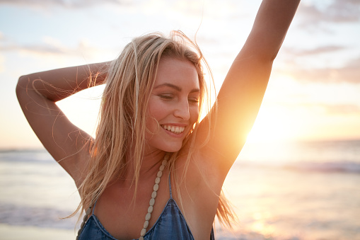 Closeup portrait of smiling young caucasian woman at the beach. Cheerful young woman enjoying a day on the sea shore at sunset.