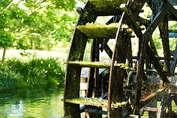 This is a horizontal, color photograph of an old fashioned, traditional wooden waterwheel turning in the river water in Nagano, Japan. Photographed with a Nikon D800 DSLR camera.