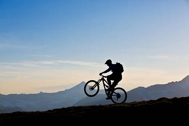 A man does a wheelie while riding his mountain bike in the Rocky Mountains of Canada. 