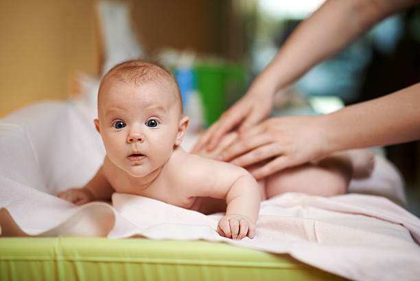 Mom makes  baby massage a little surprised stock photo