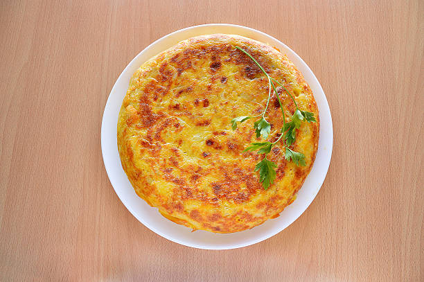 delicious spanish omelette high angle view of a spanish omelette with eggs potatoes and onion with parsley leaf on the top over a wooden table omelet rustic food food and drink stock pictures, royalty-free photos & images