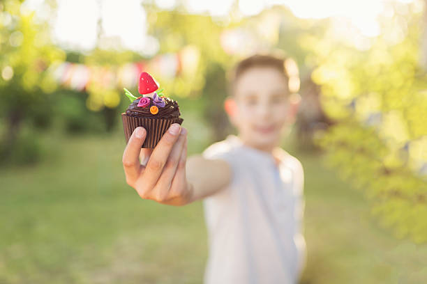This is a shallow depth of field image of homemade cupcake held by a child.