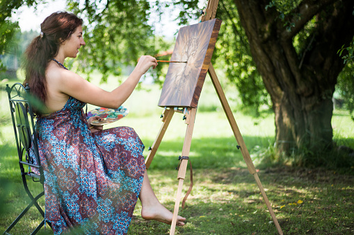 Young artist painting a tree outside in nature