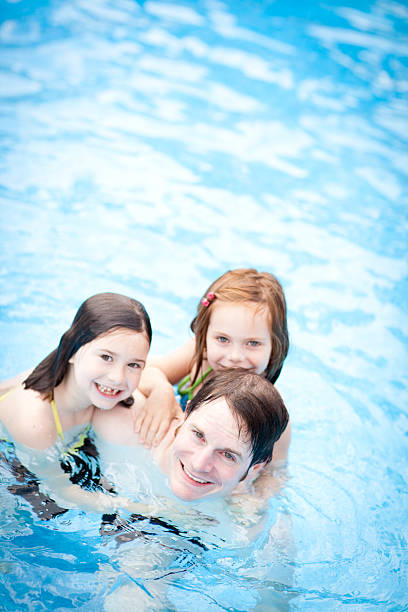istock Happy Father and Daughters Together in Swimming Pool 540495264