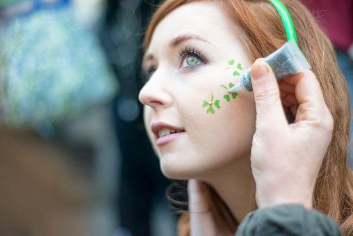 Red haired Irish girl having shamrock's painted on her face, Dublin city centre, Ireland. 