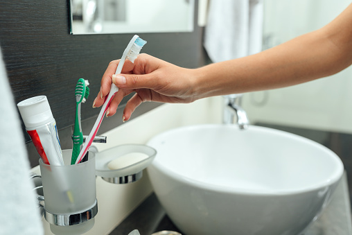 woman arm takes a toothbrush to clean teeth