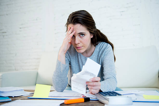 young worried woman suffering stress doing domestic accounting paperwork stock photo