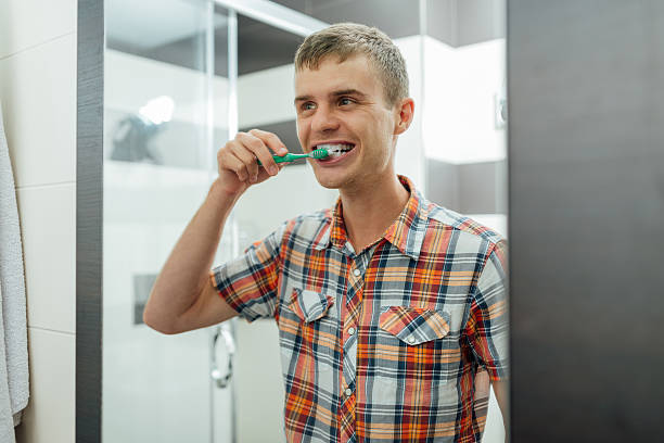 hombre guapo limpia dientes en el baño y sonriendo - dental hygiene elegance black toothbrush fotografías e imágenes de stock
