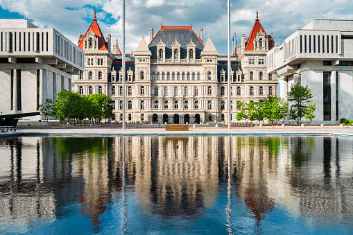 Photo of the New York State Capitol with reflections in a pond. It is the seat of the New York State government, located in downtown Albany, New York, USA.