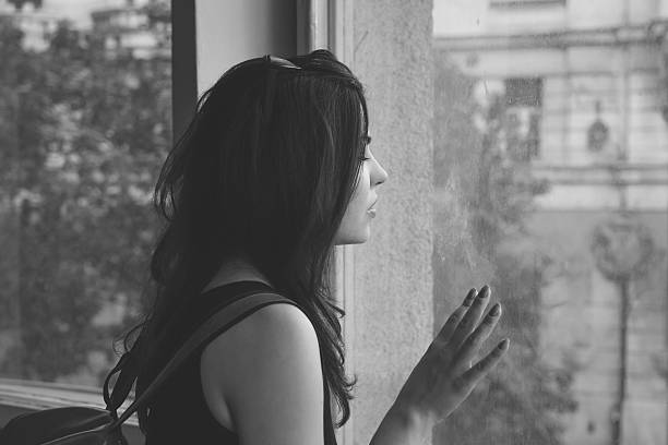 istock Young woman looking through the window 540504352