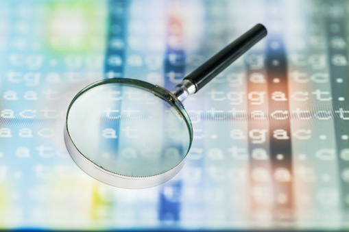 color coded DNA sequence on touch pad with magnifier glass illuminated by light