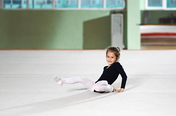 Professional sporty flexible female child stay in back bending body pose at isolated studio background, baby acrobatics indoors