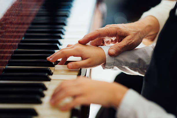 experienced hand of  old music teacher helps  child  pupil stock photo