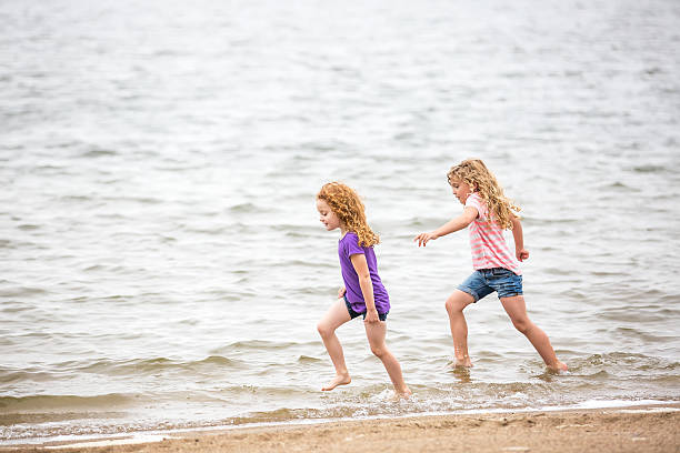 istock Two Young Girl's Running Through Water at Beach 540512362
