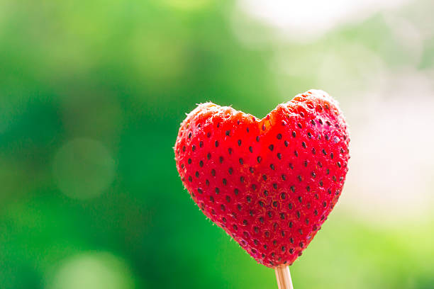 Strawberry heart shape blurry green nature background