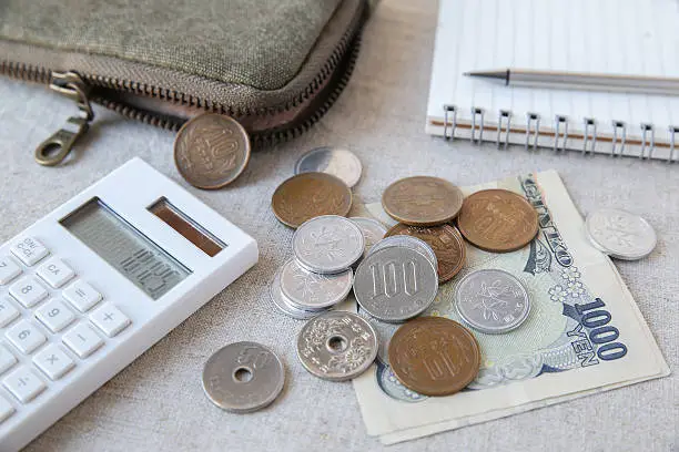 Japanese money Yen with calculator, notebook and small money pouch,selective focus on 100 yen coin