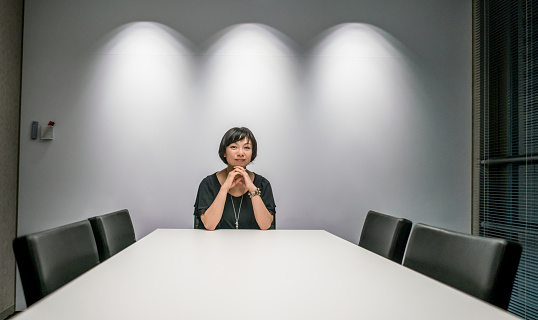Successful Asian business woman sitting at the head of a table at a boardroom - CEO concepts