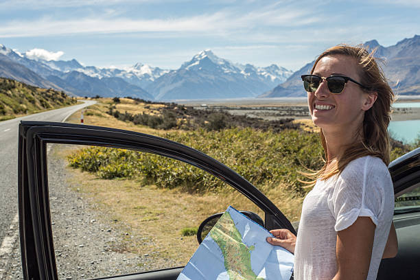 istock Young female standing out of car looking at map 540517532