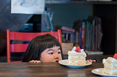 かわいい日本の幼児の女の子を見ているバースデーケーキテーブルに