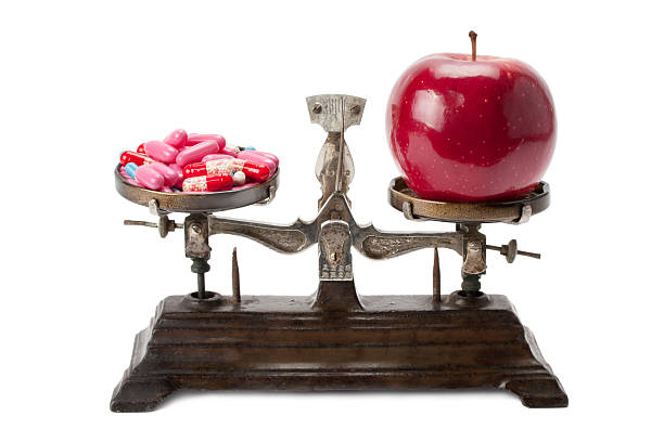 istock medicine and an apple on the scales 540519908