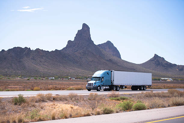 Semi truck and trailer on road with Arizona mountain Fresh popular professional big rig semi truck with a reefer trailer moving on the divided highway on a background of the famous mountain ranges bizarre in Arizona. truck in rain stock pictures, royalty-free photos & images
